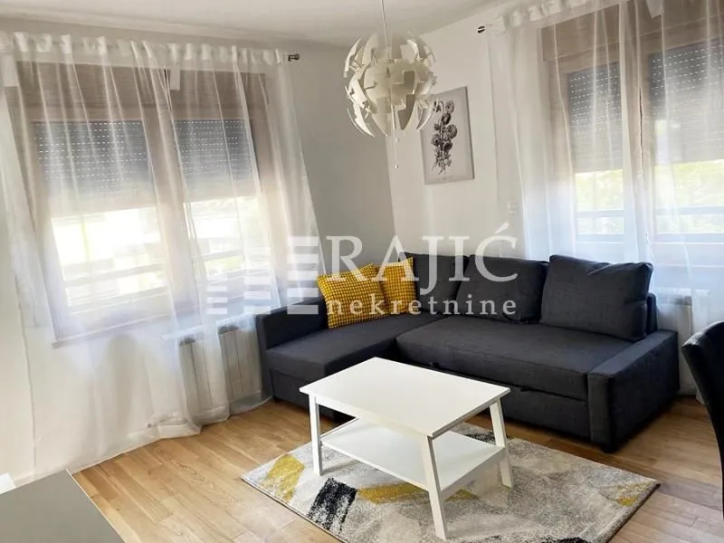 Furnished living room with a sectional sofa, coffee table, and windows with curtains.
