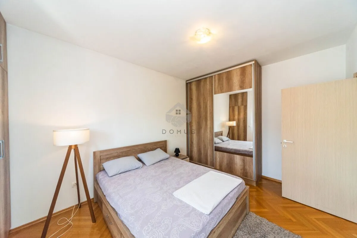 Furnished bedroom with a double bed, wooden wardrobe, and a floor lamp.