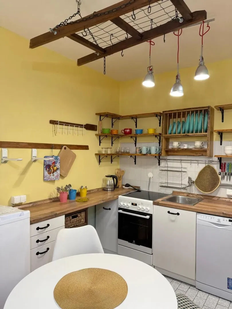 Small kitchen with yellow walls, white units, and a dining table.