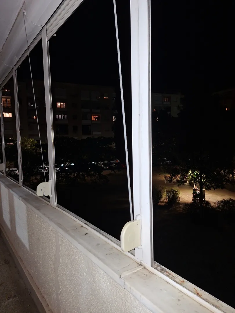 View from the glazed terrace onto the illuminated courtyard and buildings at night.