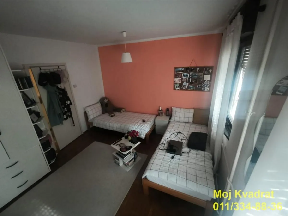 Spavaća soba sa dva kreveta i narandžastim zidom.