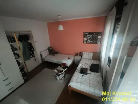 Spavaća soba sa dva kreveta i narandžastim zidom. - image 6