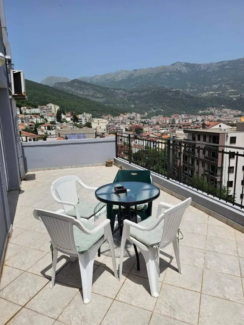 Spacious terrace with patio furniture and a view of the city and mountains.