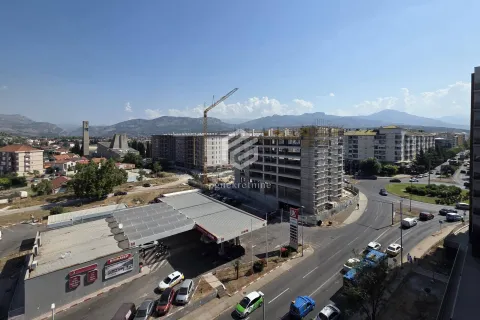 View from the window showing surrounding buildings, a construction site, and mountains in the distance. - image 16