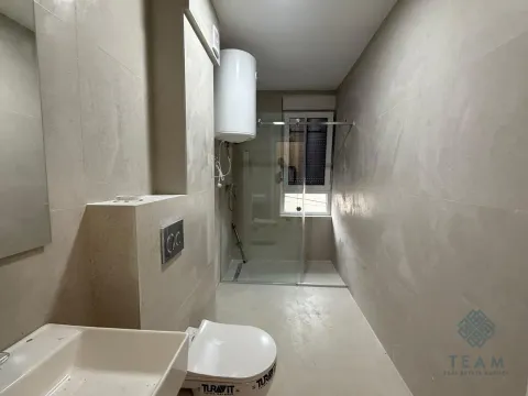 Savremeno opremljeno kupatilo sa tuš kabinom, umivaonikom i wc šoljom u bež tonovima. - image 2