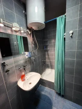 Compact bathroom with blue tiles, a washbasin, and a shower with a curtain. - image 9