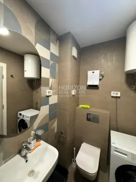 Modern bathroom with a sink, toilet, and washing machine. - image 3