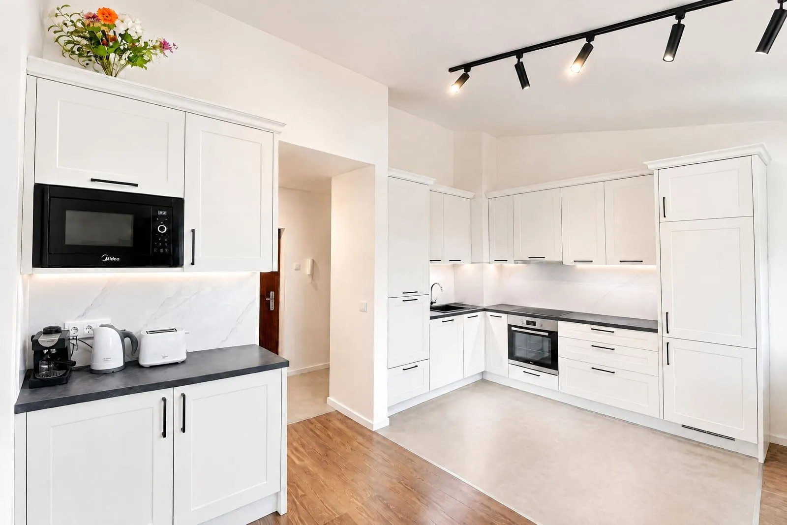 Modern white kitchen with built-in appliances and a countertop.