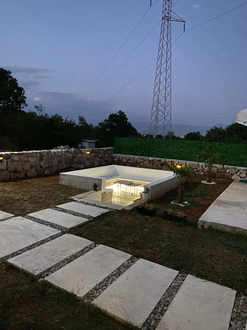 Illuminated sunken seating area in the yard with a concrete slab pathway.