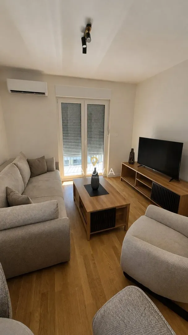 Living room with sofa, television, and wooden coffee table.