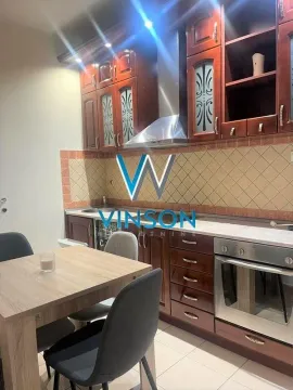 Kuhinja sa tamnim drvenim elementima, ugradnom rernom i trpezarijskim stolom sa stolicama. - image 5