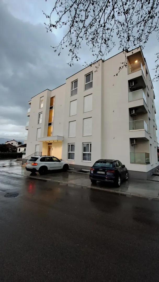 Spoljašnjost moderne stambene zgrade sa parkingom.