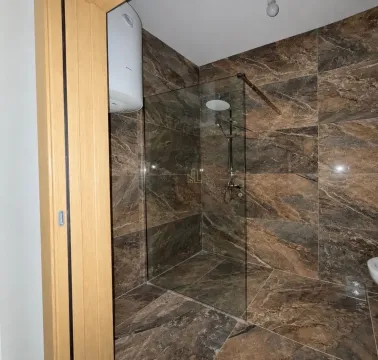 Moderne kupatilo sa tuš kabinom obloženom keramičkim pločicama u dezenu mermera. - image 6