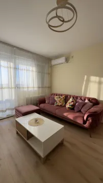 Dnevni boravak sa ljubičastom sofom, belim stočićem i balkonskim vratima. - image 4