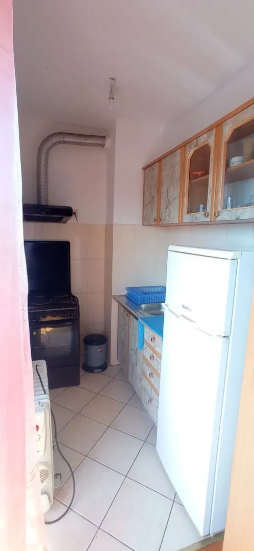 A small functional kitchen with a refrigerator, stove, and wall cabinets.