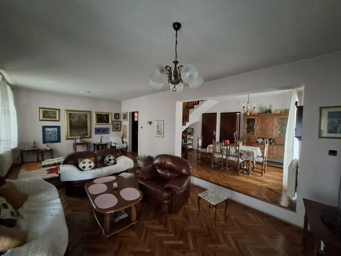 Spacious living room with seating area and a dining space in the background.