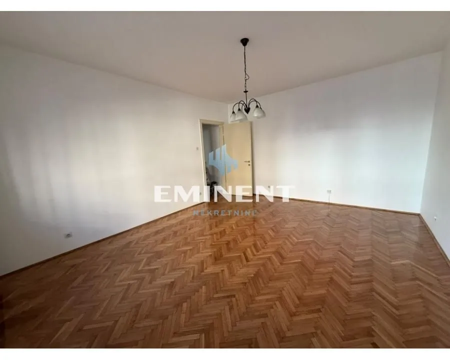 Empty room with parquet flooring and a ceiling chandelier.