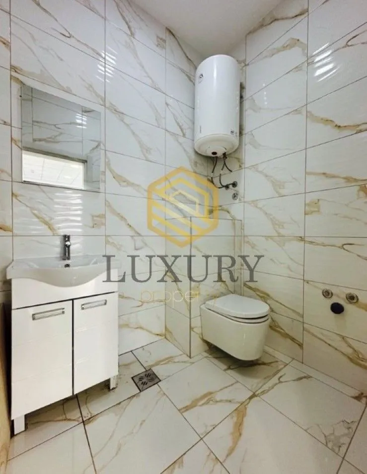 Tiled bathroom with a sink, toilet, and water heater.