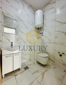 Tiled bathroom with a sink, toilet, and water heater. - image 3