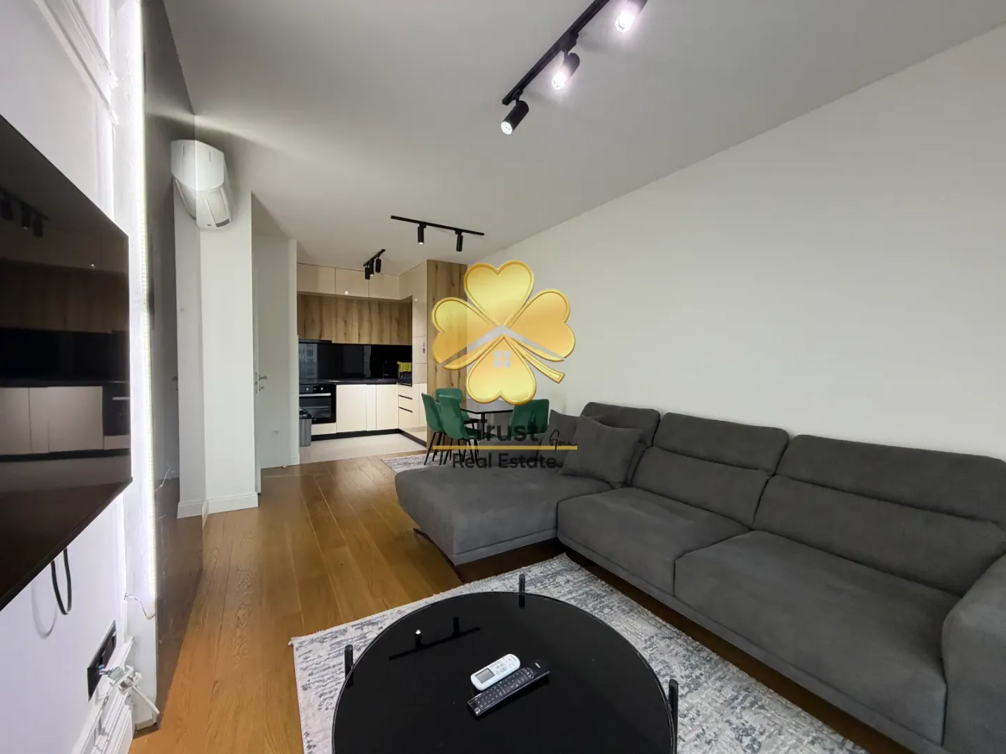 Modern living room with a sofa and dining area in the background.