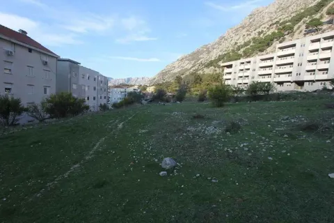 Travnata parcela okružena zgradama sa planinom u pozadini. - image 2