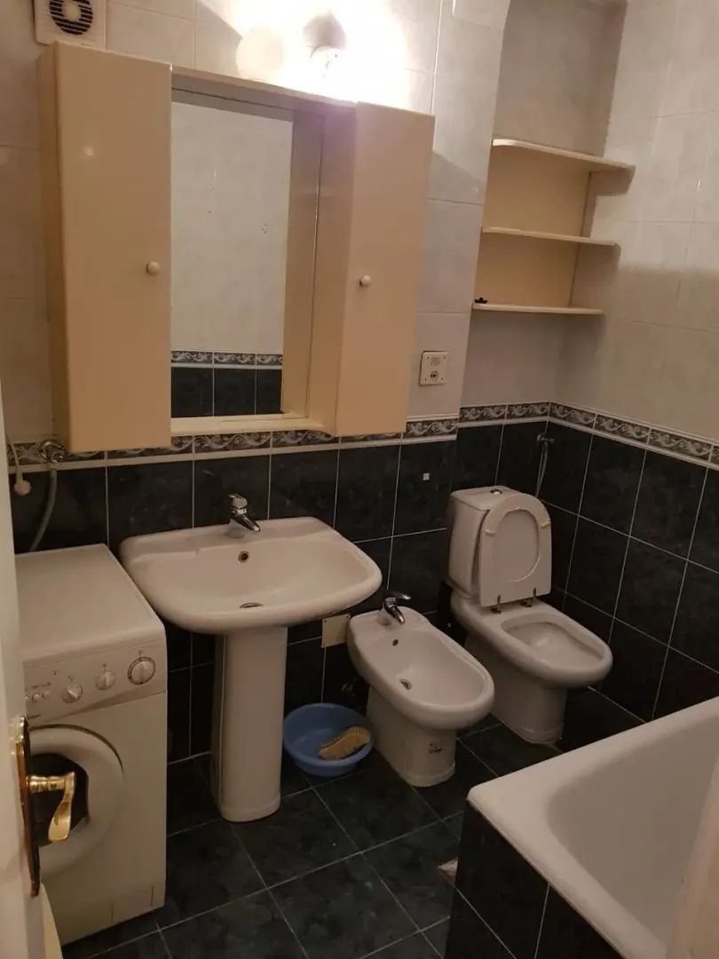 A functional bathroom with a sink, bidet, toilet, and washing machine.