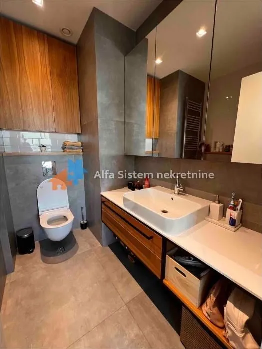 Moderno opremljeno kupatilo sa umivaonikom, ugradnim ormarićima i toaletom.