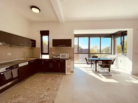 Moderna kuhinja sa tamnim elementima povezana sa trpezarijom i velikim prozorima. - image 2