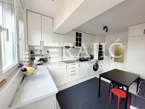 Modern white kitchen with a dining table and windows.
