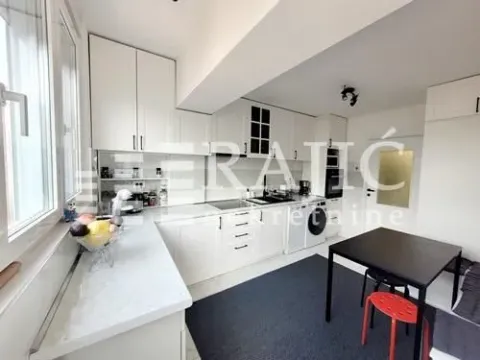 Modern white kitchen with a dining table and windows. - image 3