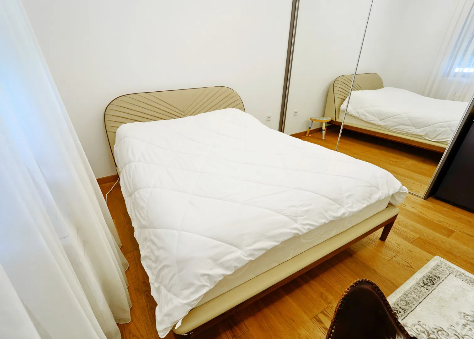 Bright bedroom with a double bed and a large built-in mirrored wardrobe.