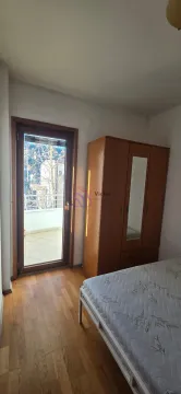 Spavaća soba sa krevetom, drvenim ormarom i izlazom na terasu. - image 6