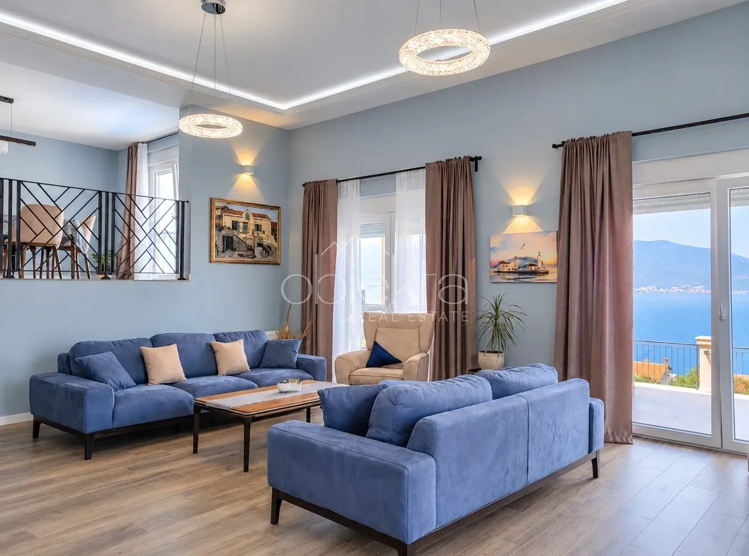 Spacious living room with blue sofas and sea view.