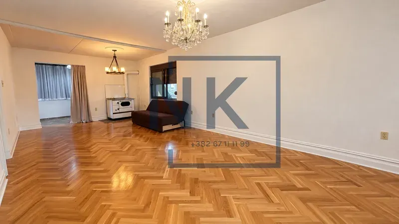 Spacious living room with wooden parquet flooring and a sofa.