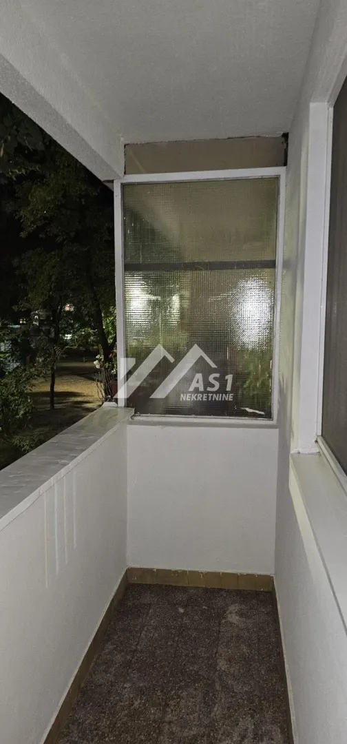 Pogled na natkriveni balkon sa belom ogradom noću.