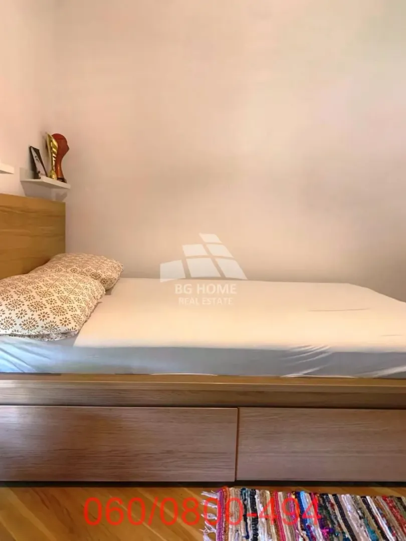 Manja spavaća soba sa drvenim krevetom i policom na zidu.