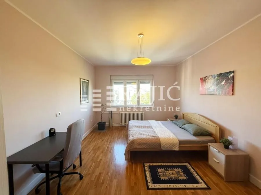 Spacious bedroom with a double bed, desk, and hardwood flooring.