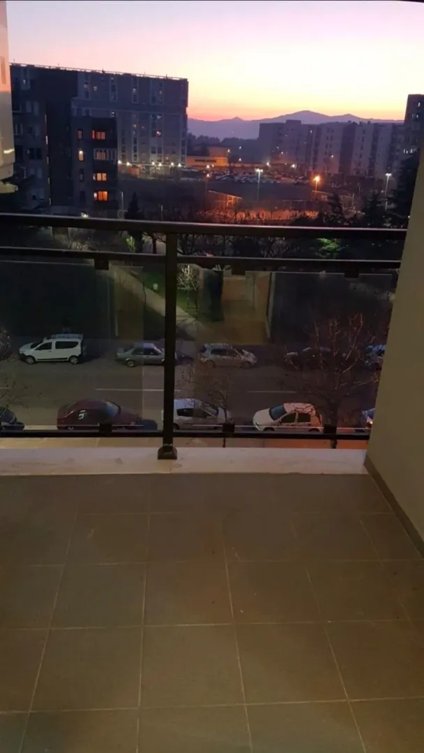 Pogled sa balkona na gradsku ulicu i zgrade u sumraku.