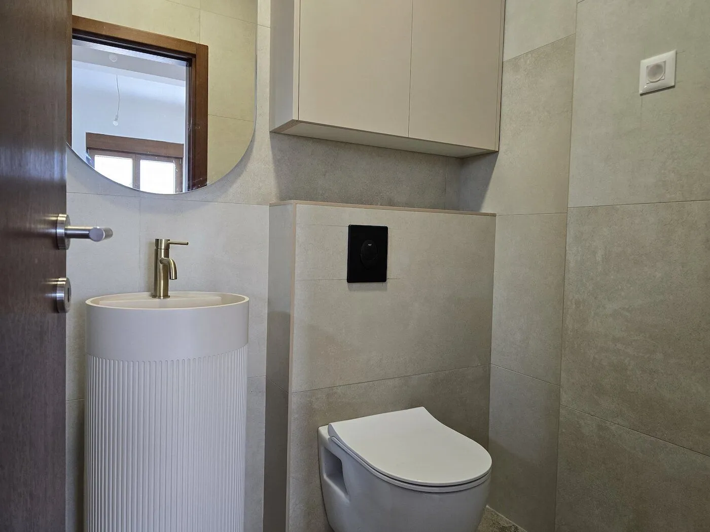 Modernly equipped bathroom with a washbasin, toilet, and mirror.