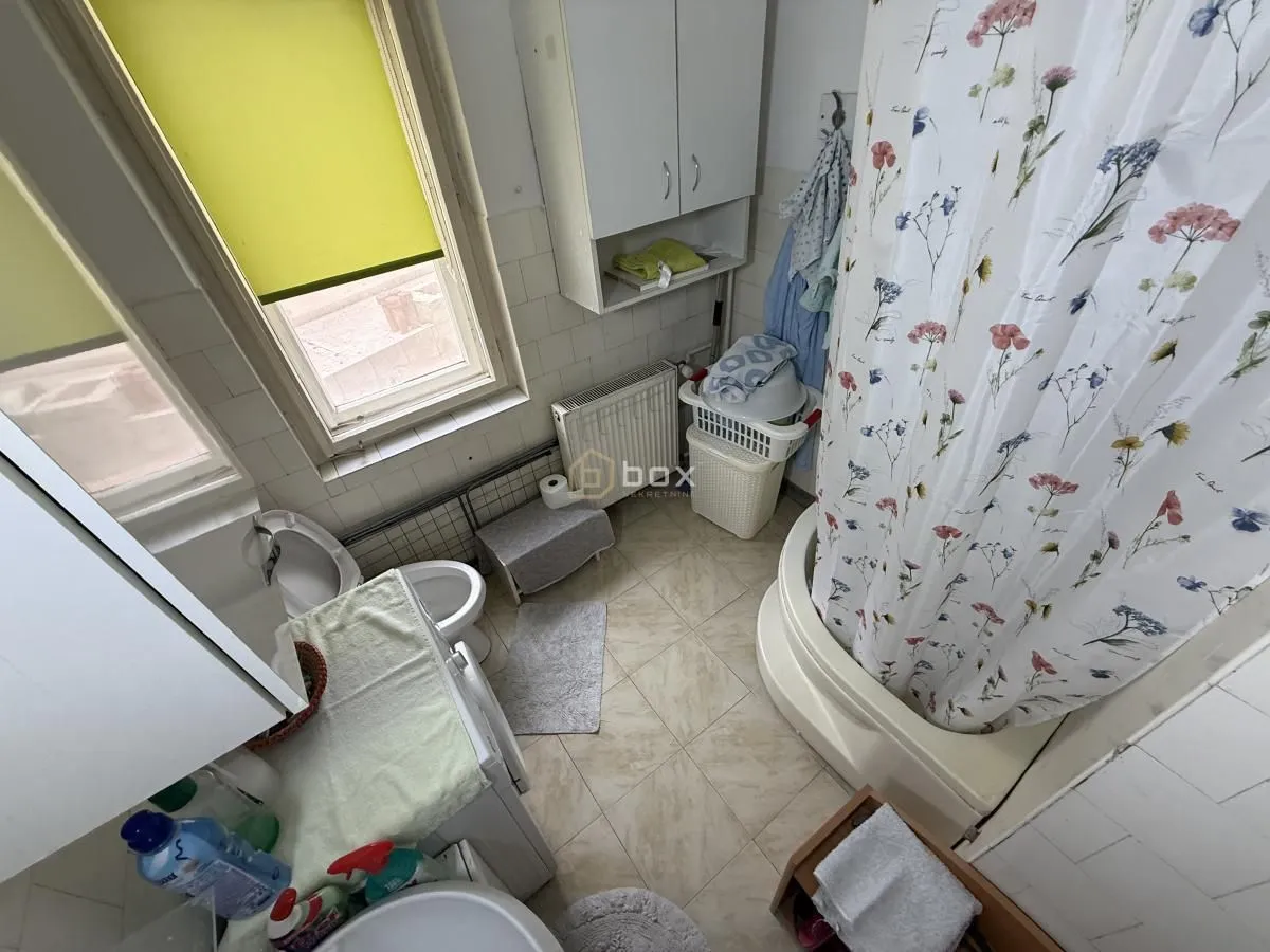 Pogled odozgo na kupatilo sa tuš kabinom, WC šoljom i prozorom.