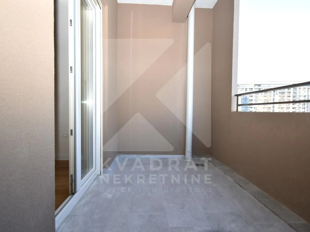 Nenamješten balkon sa popločanim podom i ogradom.