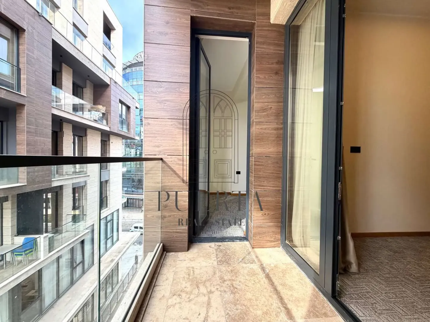 Modern balcony with glass railing and view of buildings.