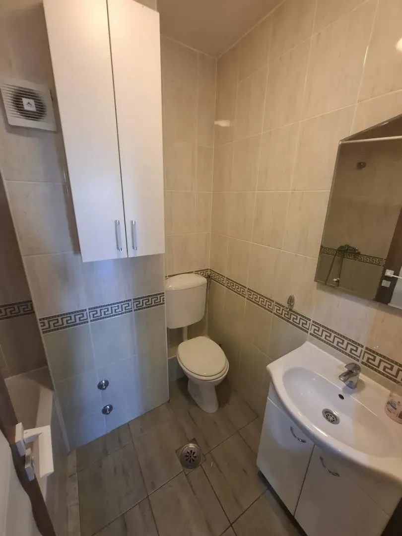 Kompaktno kupatilo sa umivaonikom, WC šoljom i zidnim ormarićem.