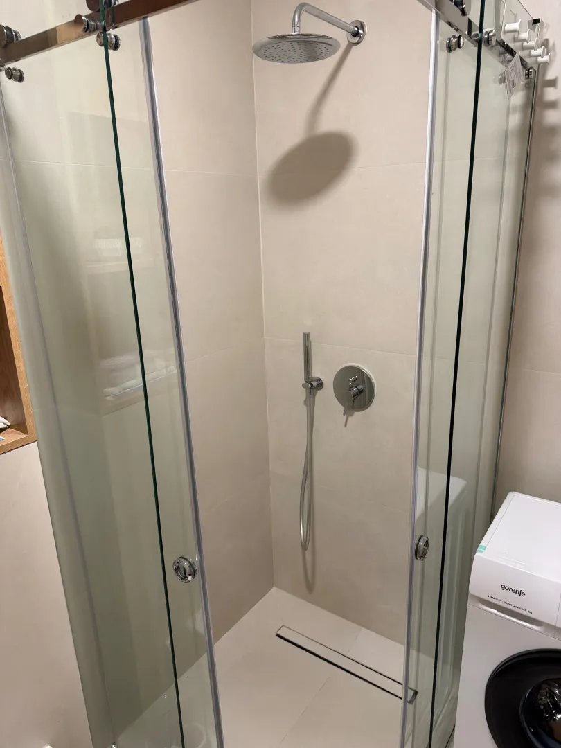 Modern walk-in shower with glass screen in a fitted bathroom.