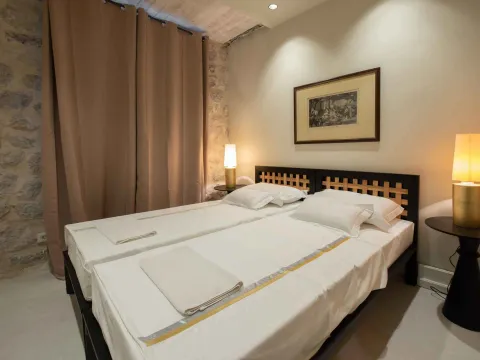 Bedroom with two single beds and a stone wall. - image 7