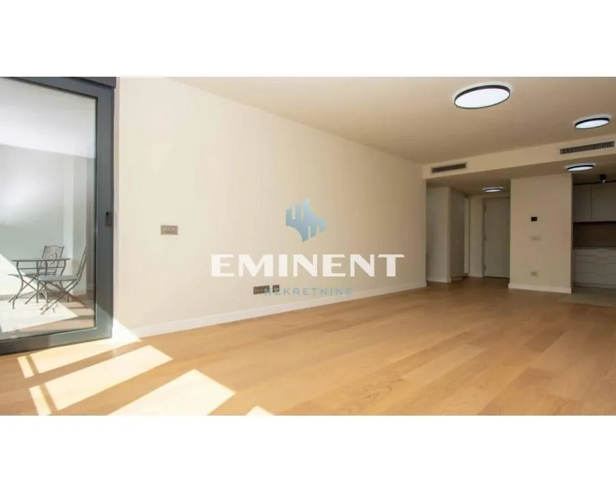 Empty living room with wooden flooring and access to the terrace.