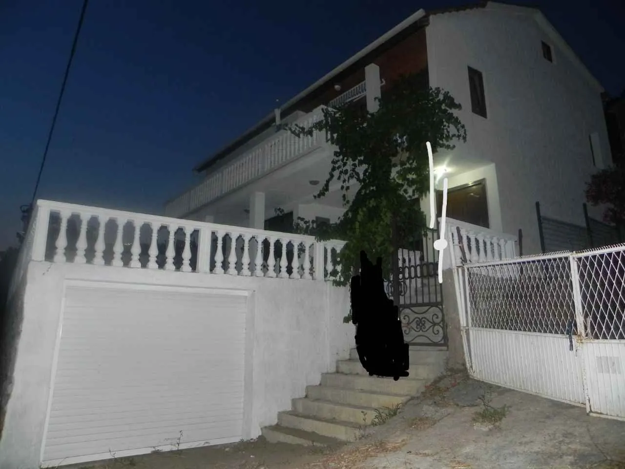 Vanjski izgled dvospratne kuće sa garažom.