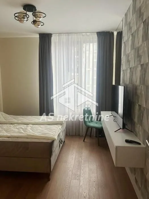 Furnished bedroom with a double bed, TV, and a desk.