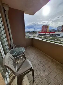 Balcony with a table, chairs, and city view. - image 9