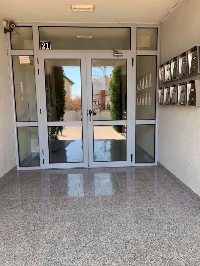 Ulaz u stambenu zgradu sa staklenim vratima i poštanskim sandučićima.